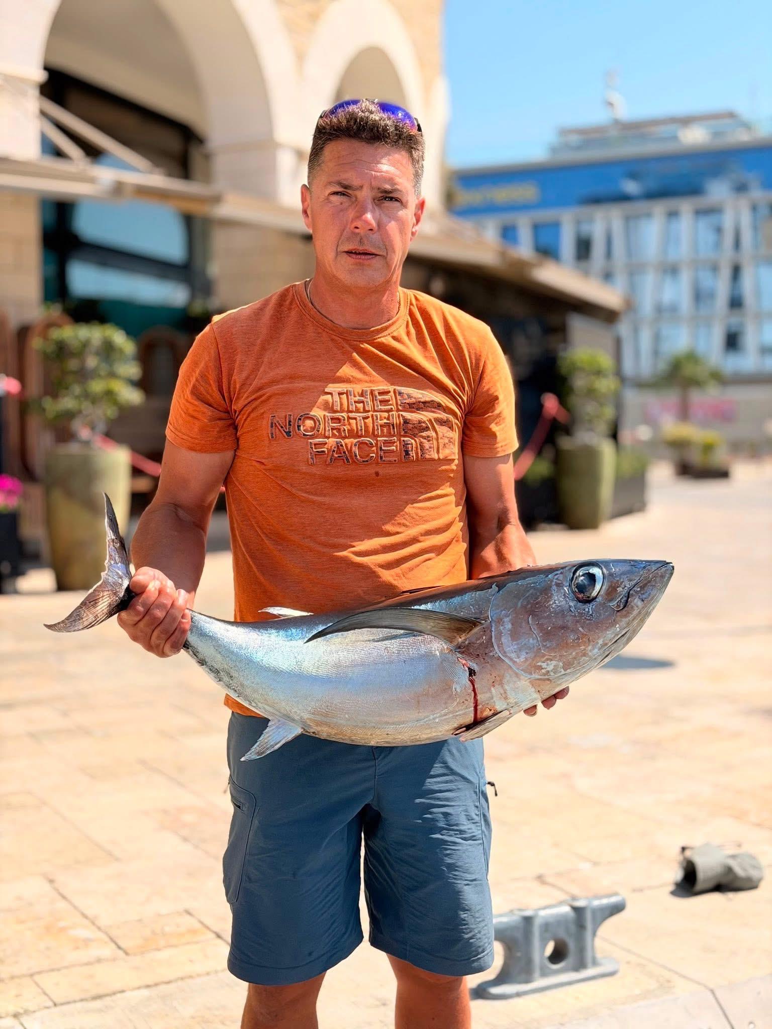 The sailor holding a bluefin tuna on the back deck // Моряк держит тунца на кормовой палубе // Ο ναυτικός κρατά έναν τόνο στο κατάστρωμα